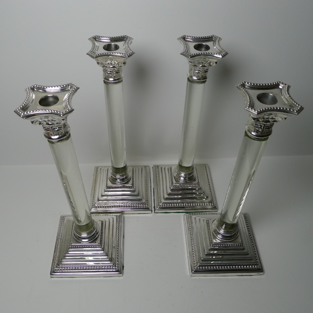 A set of four Victorian silver-plated candlesticks featuring clear glass column shafts, cast Corinthian capitals, and square stepped bases. View VIII