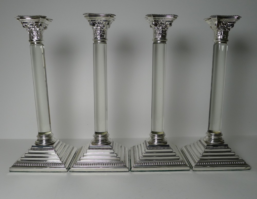 A set of four Victorian silver-plated candlesticks featuring clear glass column shafts, cast Corinthian capitals, and square stepped bases. View IX