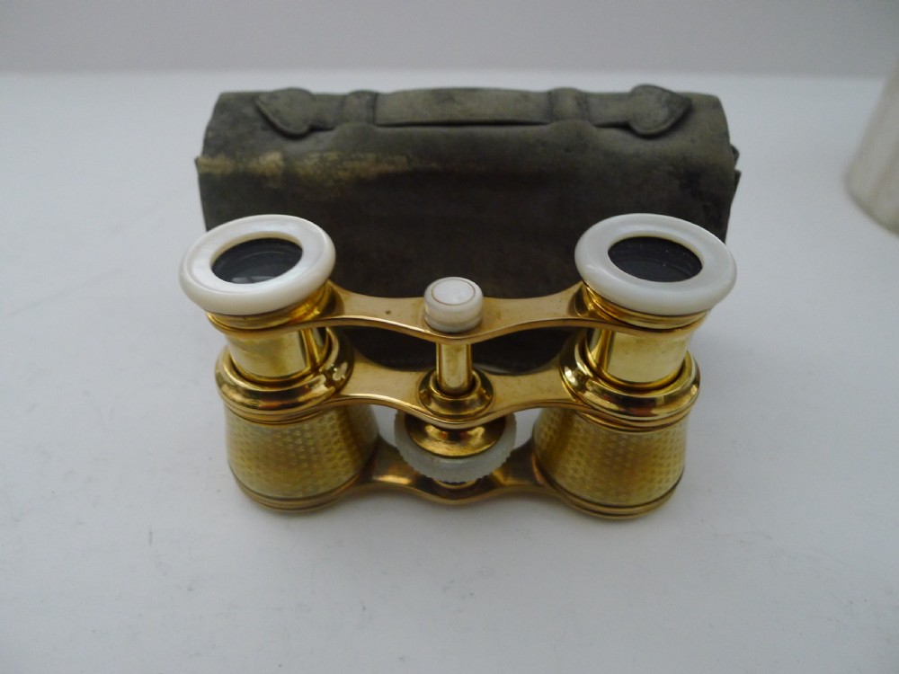 A pair of Edwardian golden guilloche enamel opera glasses with mother-of-pearl eye cups set in front of a grey leather pouch. View VII