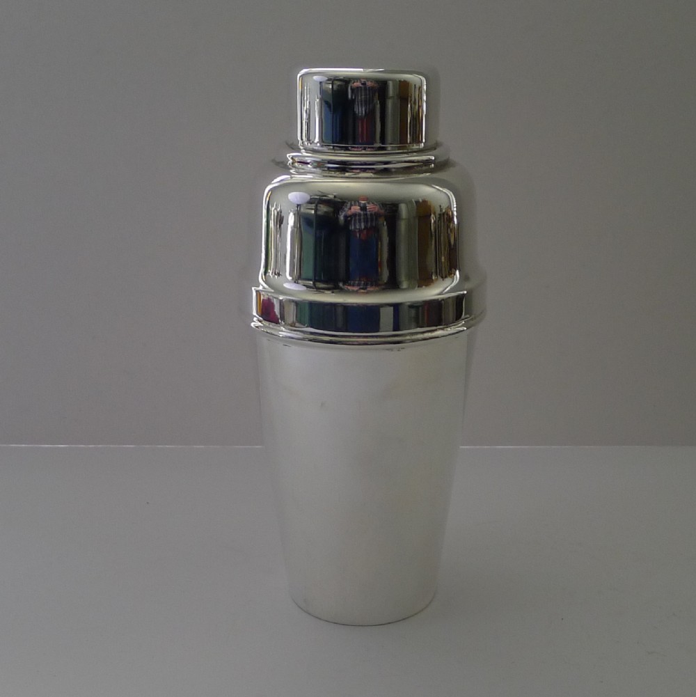 A polished silver-plated Art Deco cocktail shaker featuring a tapered body and stepped lid structure.