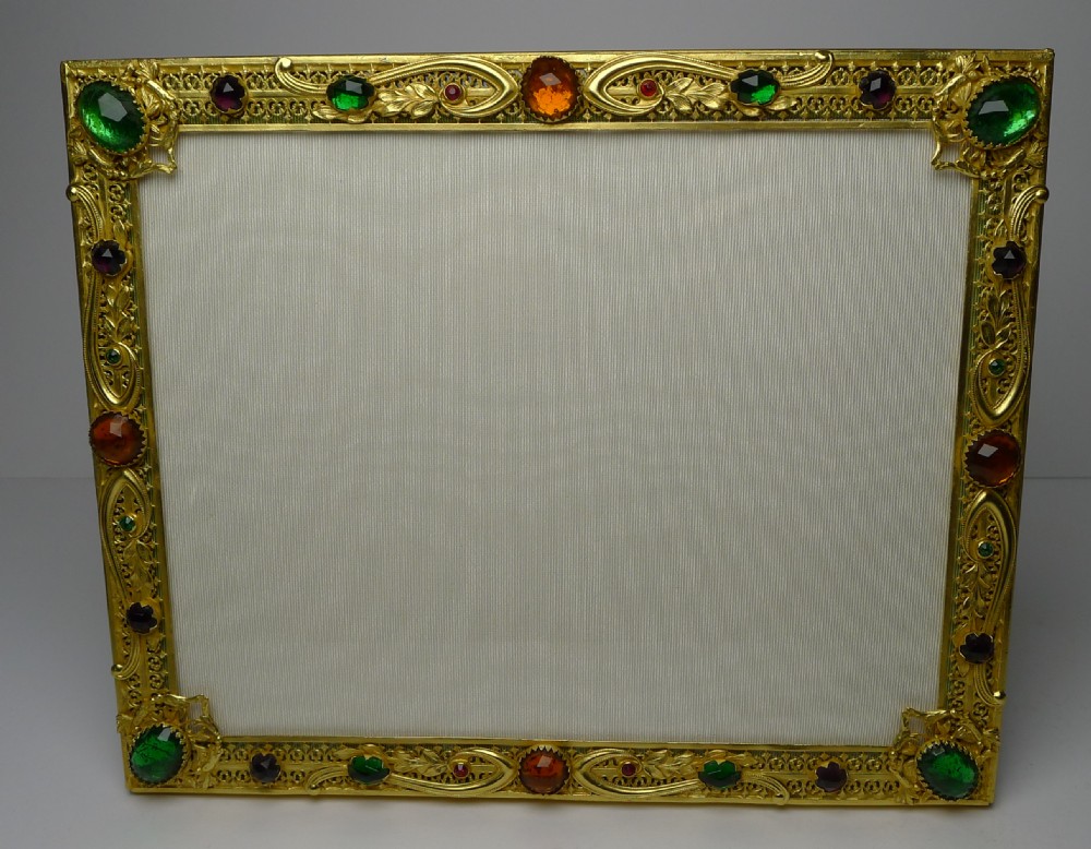 A rectangular French gilded bronze picture frame decorated with filigree scrollwork and inset with multi-coloured cabochon paste stones. View VIII