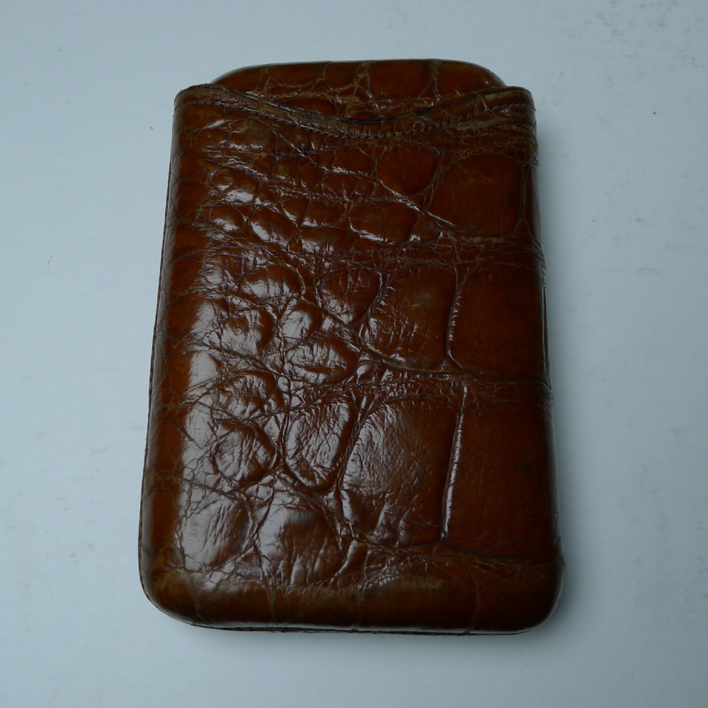 A late Victorian brown crocodile leather pocket cigar case displaying natural scale textures and stitched edges.