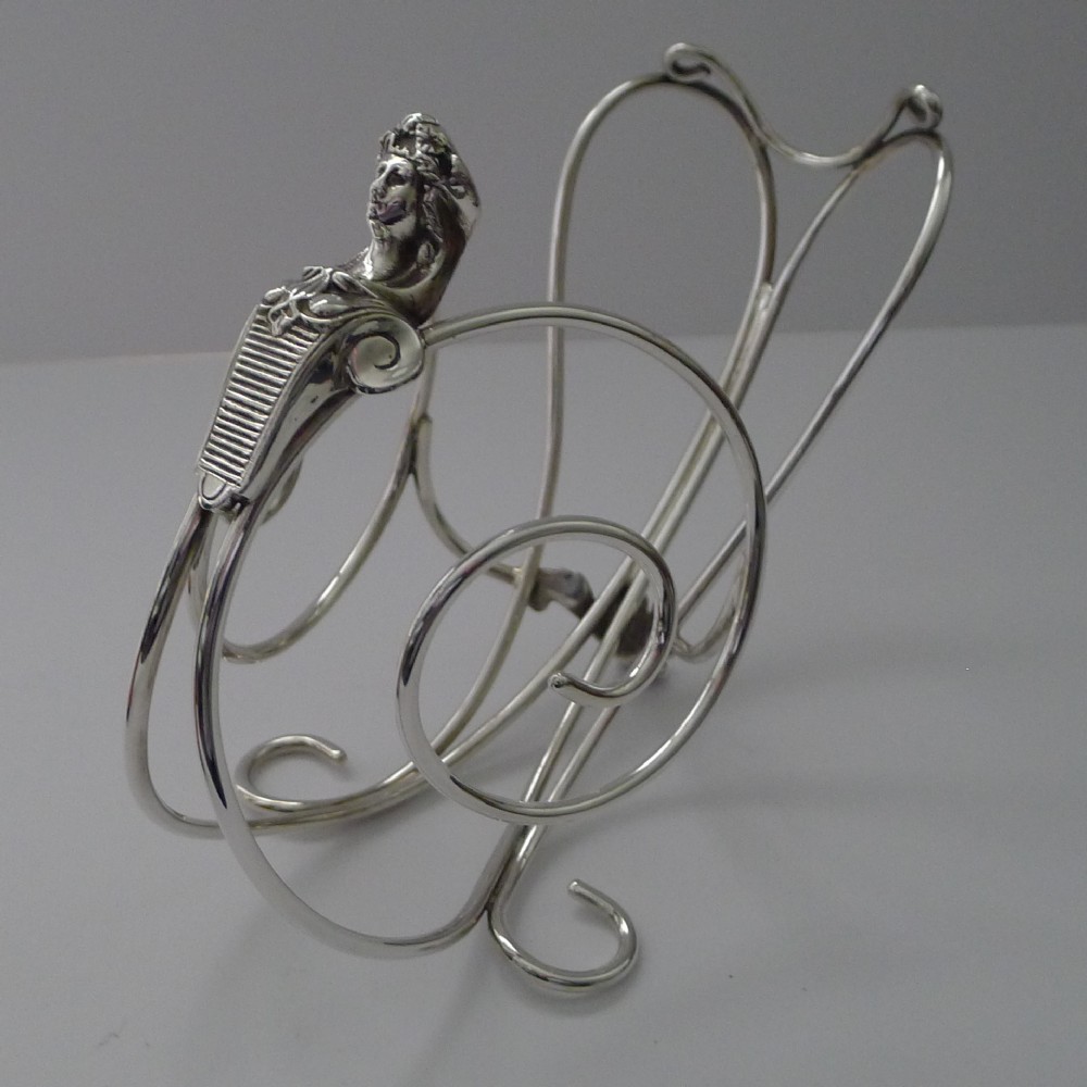 A vintage Elkington silver-plated wine bottle holder featuring intricate wirework and a figural handle.