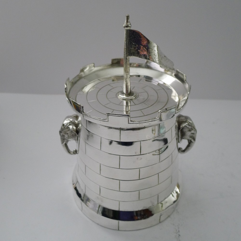 A silver-plated Victorian biscuit box designed in the shape of a crenellated castle tower with elephant head handles and a flag finial. View XIII