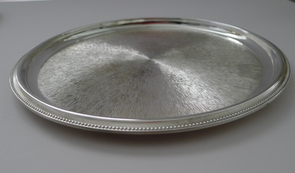 A circular silver-plated cocktail tray featuring a textured sunburst pattern at the centre and a beaded rim. View IV