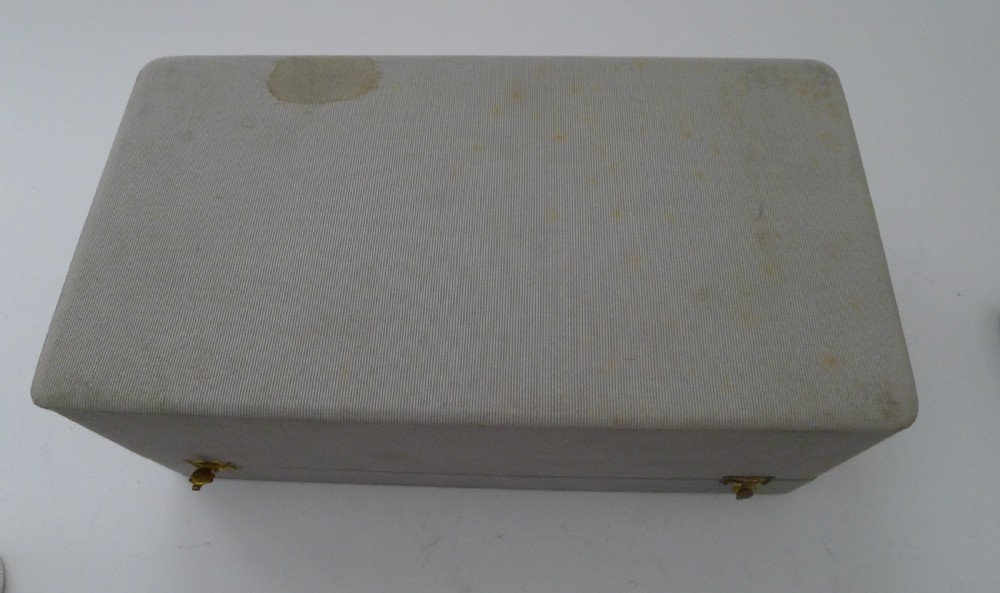 A vintage sterling silver smoking compendium set featuring four horseshoe-shaped ashtrays and a central cylinder within an open silk-lined presentation case. View IX