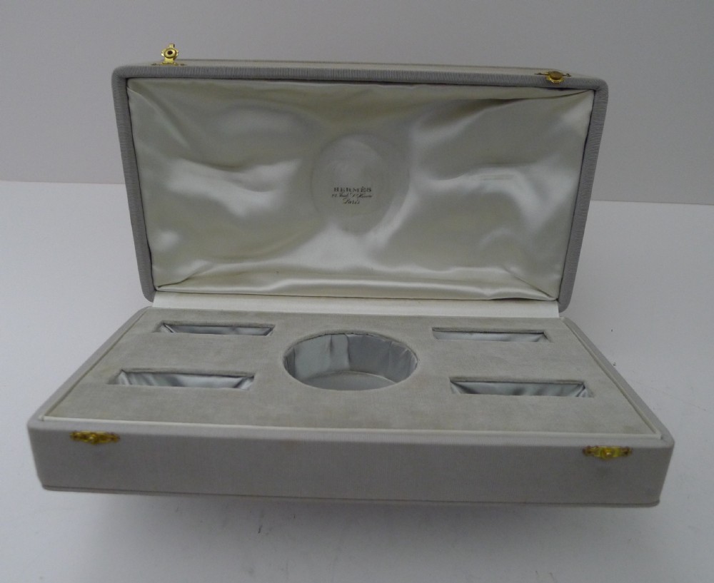 A vintage sterling silver smoking compendium set featuring four horseshoe-shaped ashtrays and a central cylinder within an open silk-lined presentation case. View X