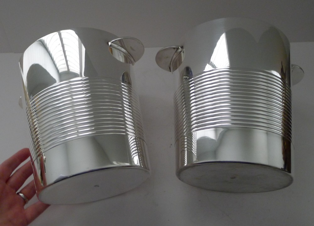 A pair of polished silver-plated Art Deco champagne buckets featuring central horizontal reeded bands and small rectangular side handles. View VI