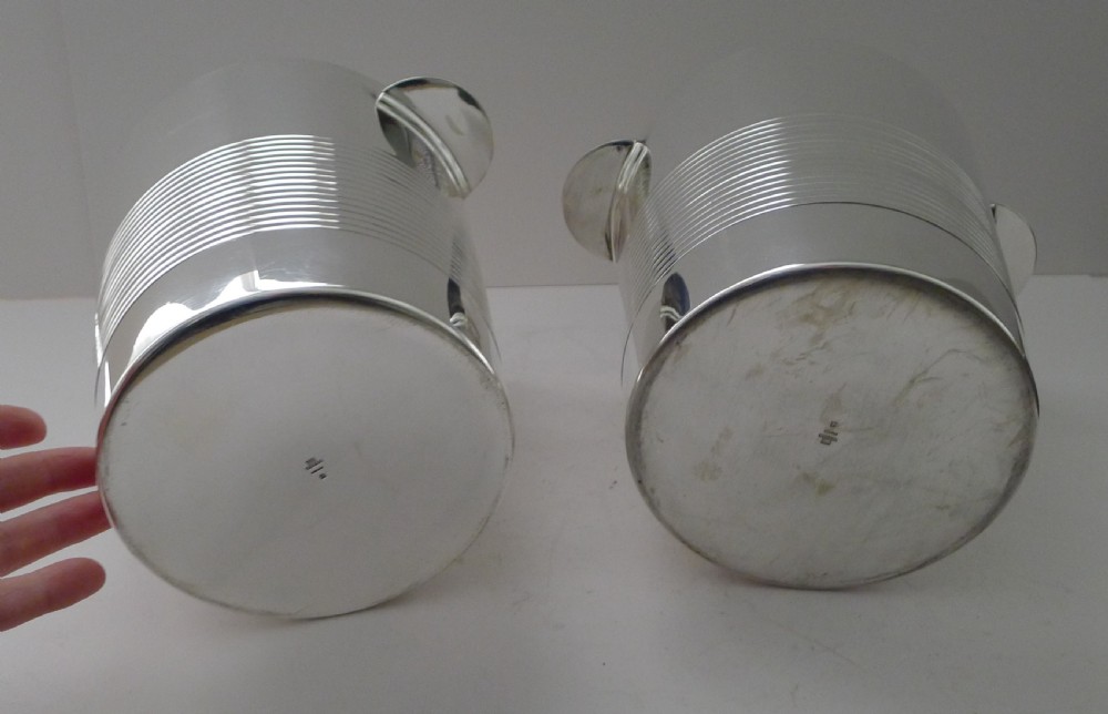 A pair of polished silver-plated Art Deco champagne buckets featuring central horizontal reeded bands and small rectangular side handles. View VII