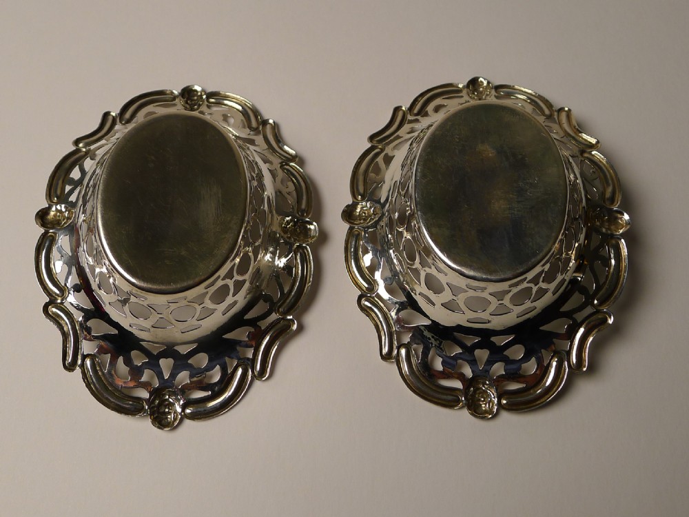 A pair of oval pierced sterling silver decorative baskets featuring scalloped borders and dark tortoiseshell bases. View III