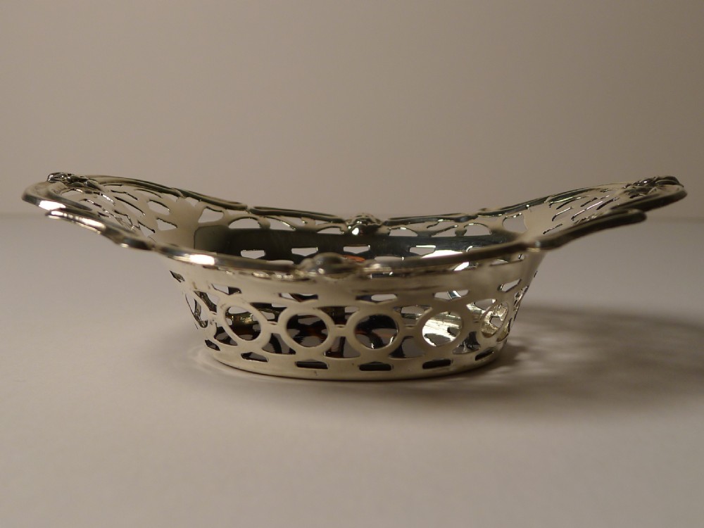 A pair of oval pierced sterling silver decorative baskets featuring scalloped borders and dark tortoiseshell bases. View V