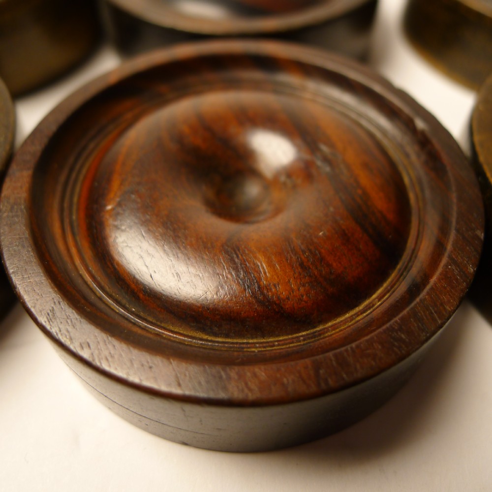 A set of thirty turned dark wooden gaming counters arranged in a grid, featuring central bone inlays and raised circular rims. View II