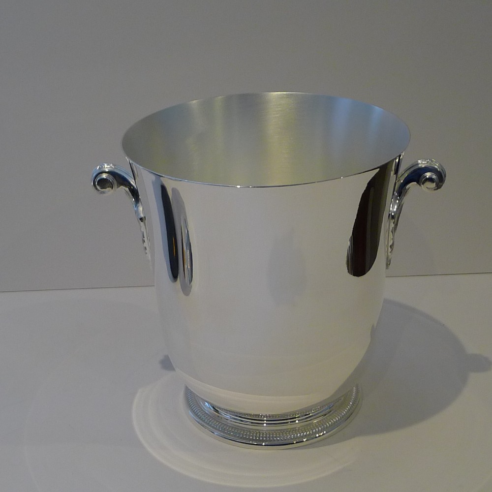 A polished silver-plated French champagne bucket featuring dual scroll side handles and a detailed beaded rim around the circular base.