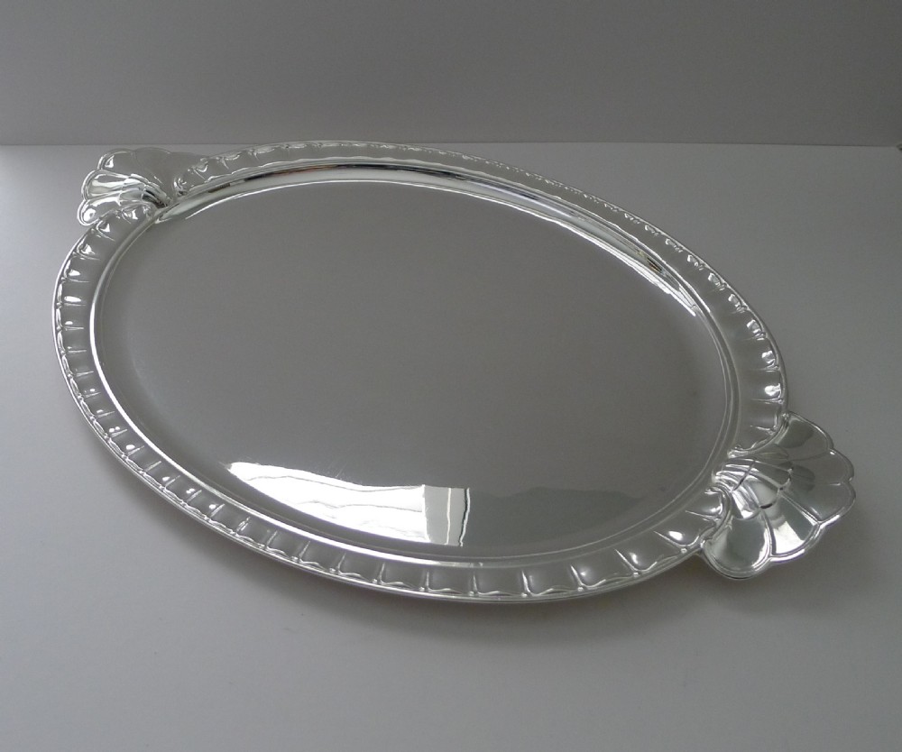 A polished oval silver-plated Art Deco tray featuring fluted edges and scalloped shell handles on each end. View VII