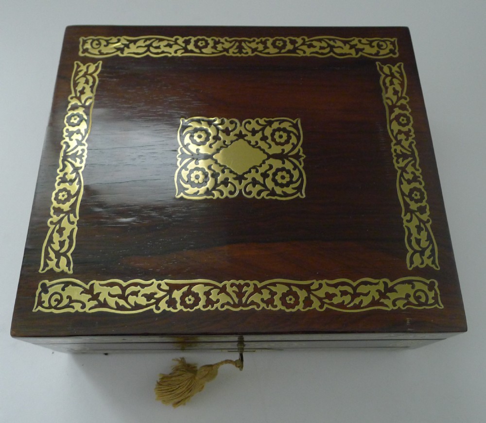 Rectangular dark rosewood jewellery box with elaborate cut-brass floral inlay across the lid and front panel, fitted with a key and tassel. View III