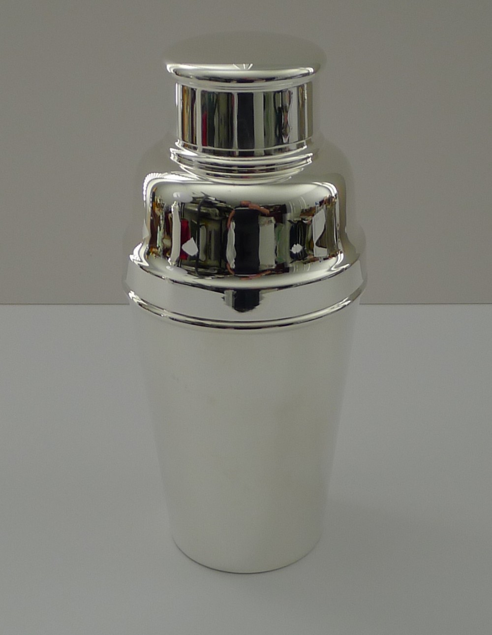 A polished silver-plated Art Deco cocktail shaker featuring a tapered smooth body and a stepped removable cap.