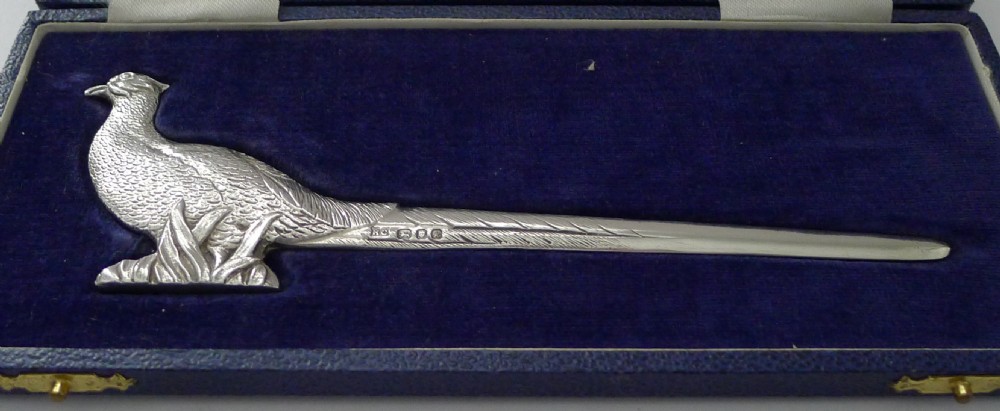 A solid sterling silver letter opener crafted in the form of a detailed standing pheasant, resting inside a blue velvet-lined presentation box. View VIII