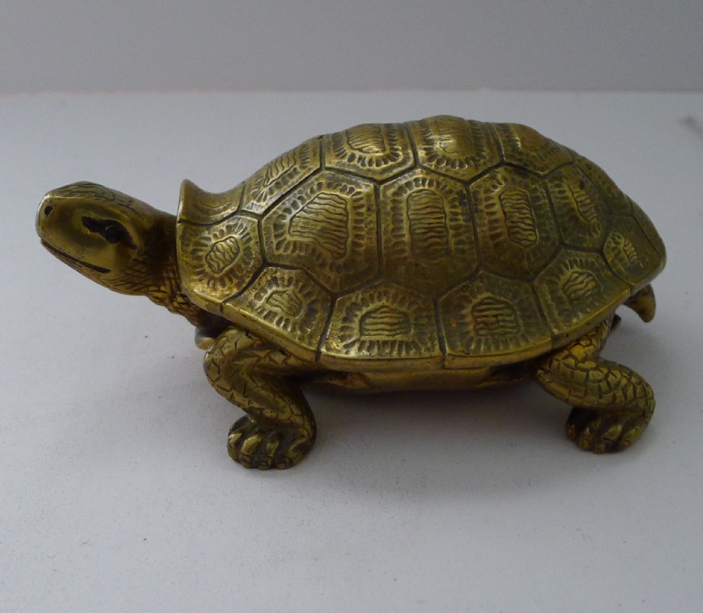 A cast brass turtle figurine with a hinged shell serving as a novelty desk inkwell.