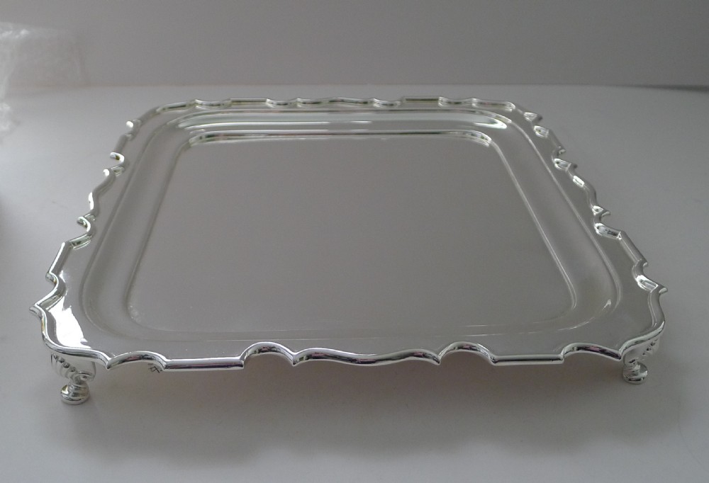 A square silver-plated cocktail tray featuring a raised scalloped edge and a smooth central field. View III