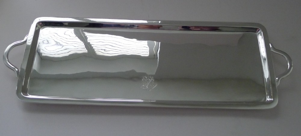 A long rectangular silver-plated tray with side handles and an engraved crest on the surface. View III