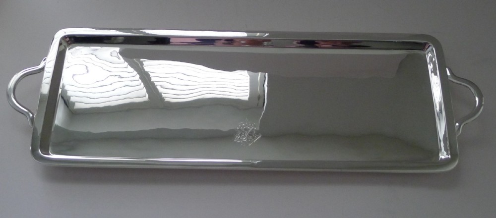 A long rectangular silver-plated tray with side handles and an engraved crest on the surface. View V