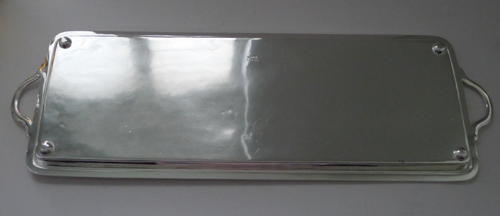 A long rectangular silver-plated tray with side handles and an engraved crest on the surface. View VIII