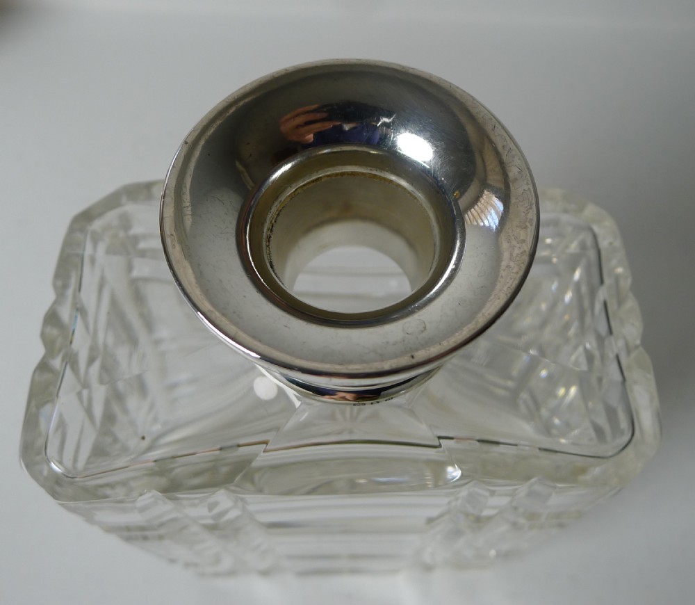 A square-form Art Deco cut crystal spirit decanter featuring geometric faceting, a faceted glass stopper, and a hallmarked sterling silver collar. View III