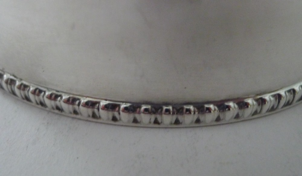 A cylindrical solid sterling silver biscuit box featuring a fitted lid and beaded decorative borders along the upper and lower edges. View XII