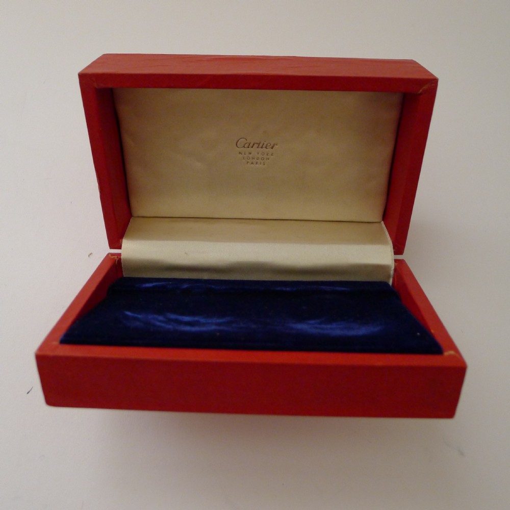 A pair of pierced sterling silver napkin rings with foliage motifs resting inside a red Cartier presentation box. View X