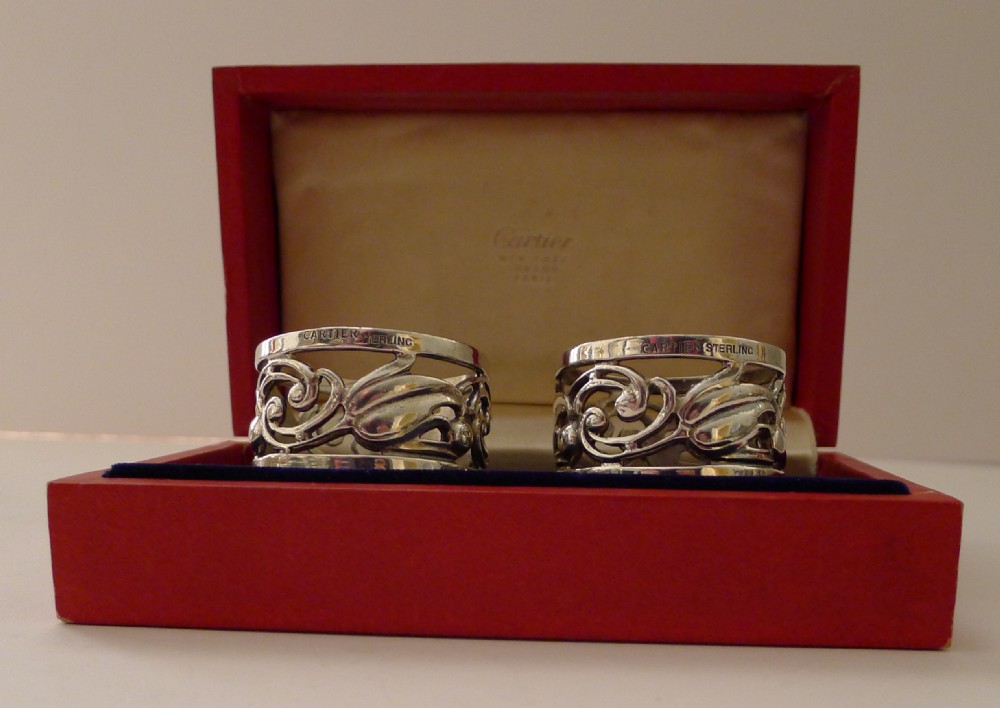 A pair of pierced sterling silver napkin rings with foliage motifs resting inside a red Cartier presentation box. View XII