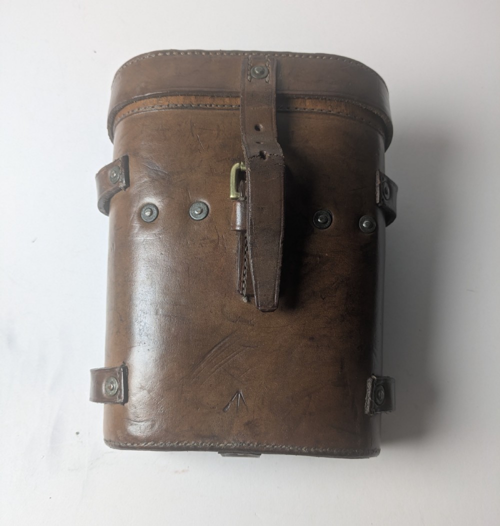 A pair of antique brass field binoculars with textured brown leather grips alongside a fitted brown leather carrying case with straps. View XII