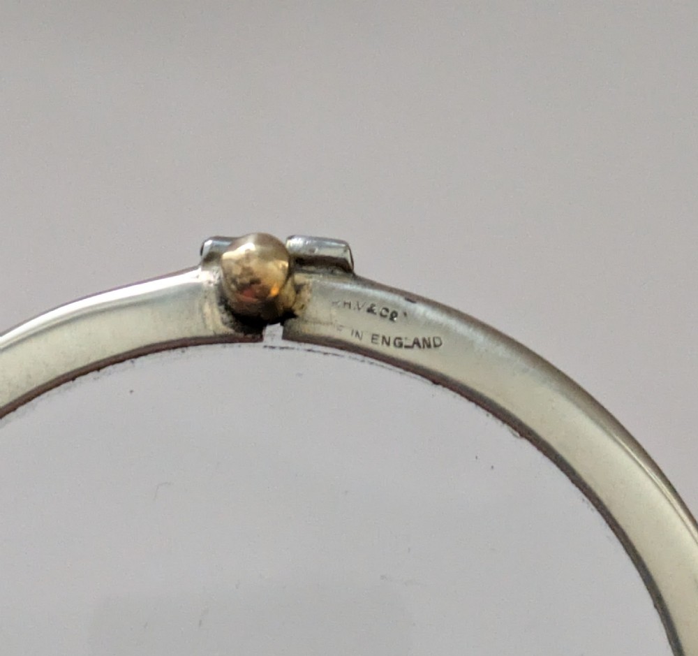 An antique circular magnifying glass with a silver-plated bezel, a dark turned wood handle, and a brass end cap. View VII