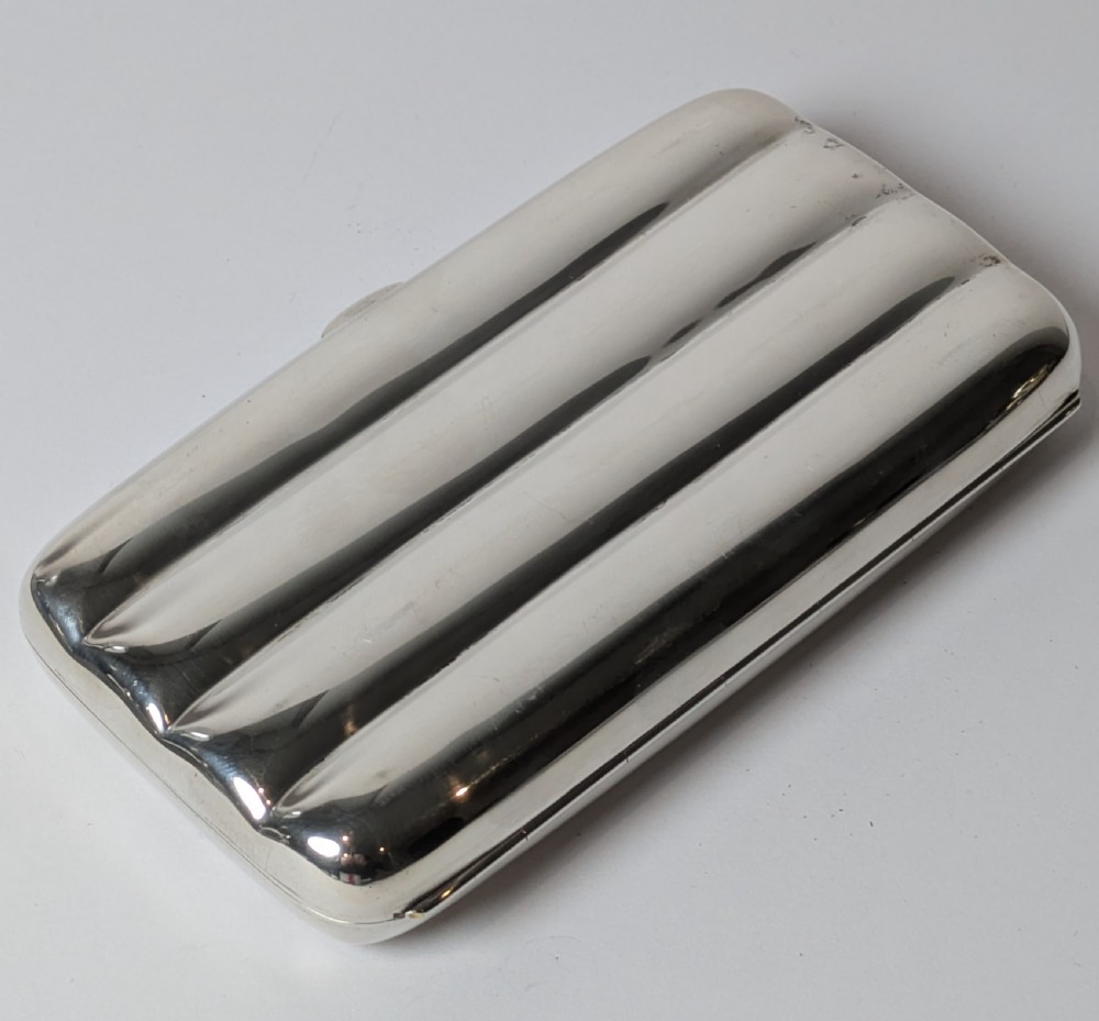 A polished sterling silver hinged cigar case featuring four rounded longitudinal compartments and smooth exterior edges.