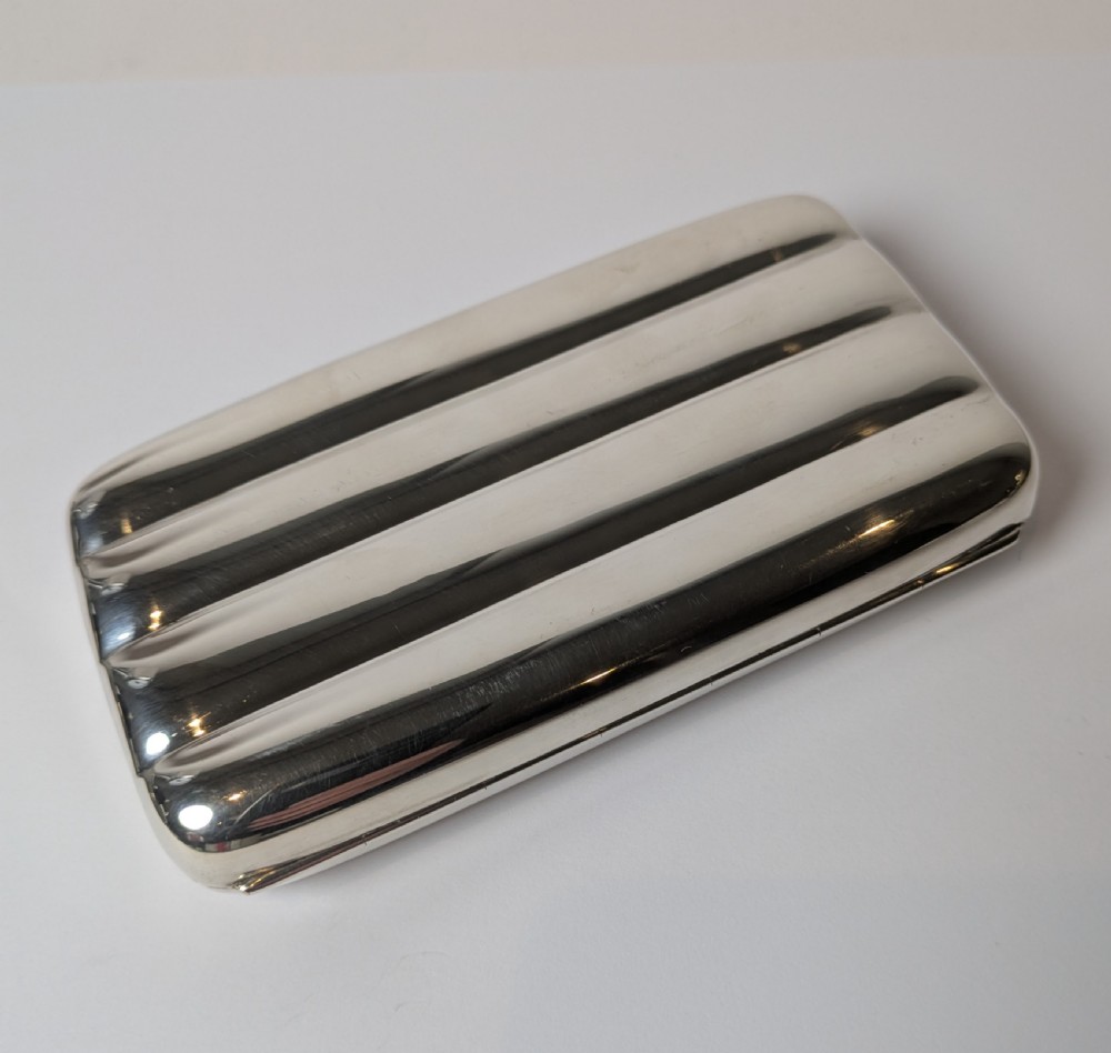 A polished sterling silver hinged cigar case featuring four rounded longitudinal compartments and smooth exterior edges. View III