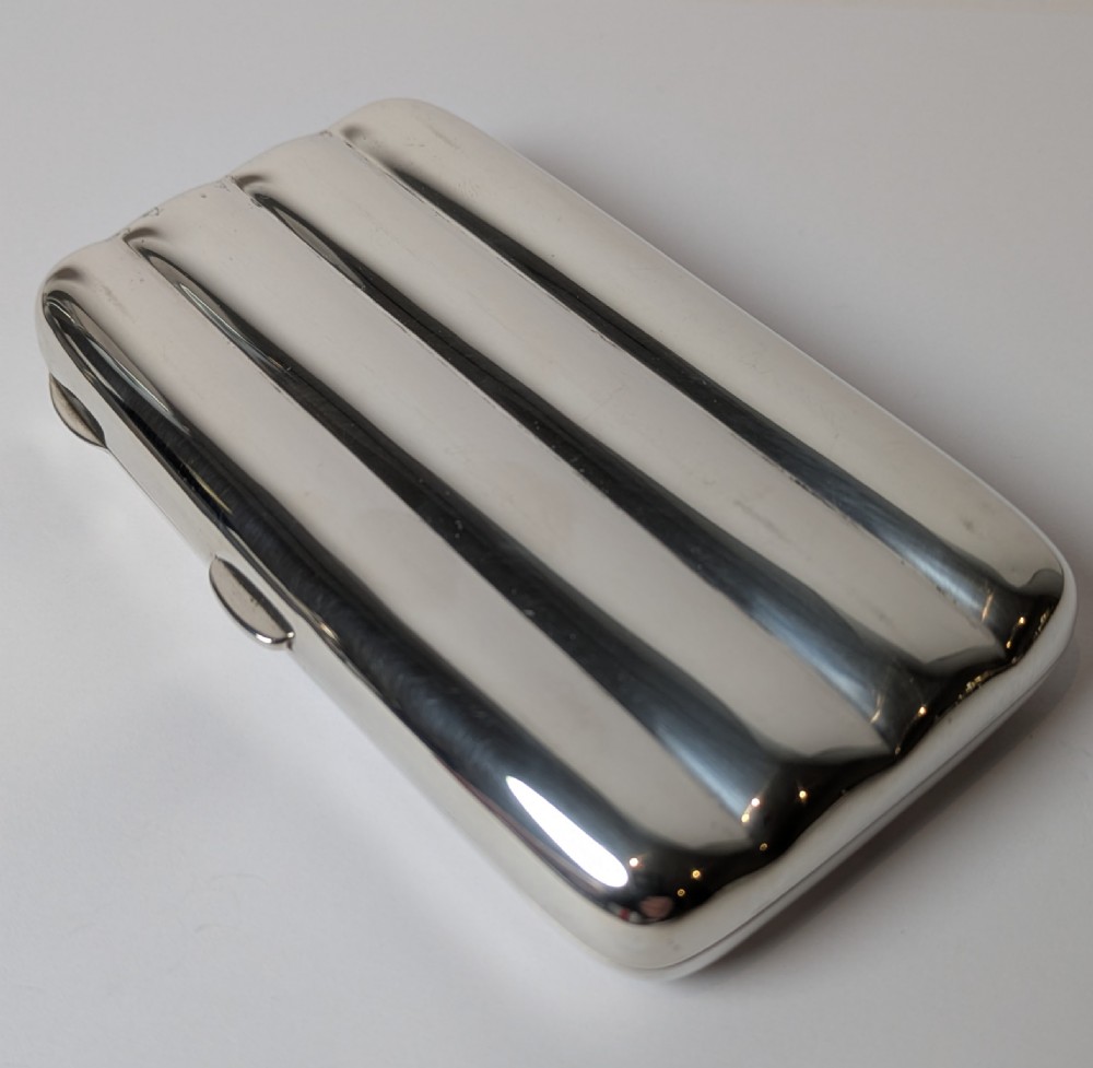 A polished sterling silver hinged cigar case featuring four rounded longitudinal compartments and smooth exterior edges. View VI