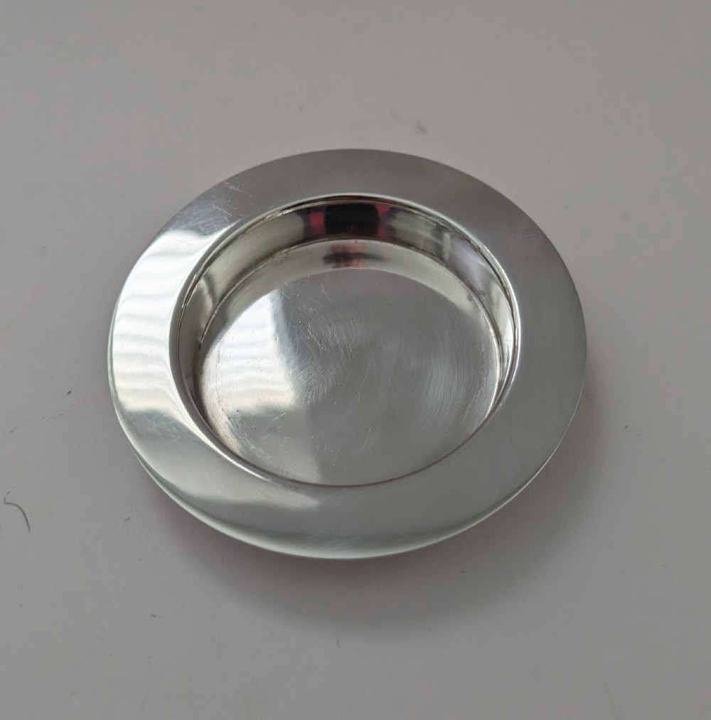 A boxed set of six circular sterling silver butter dishes paired with six matching butter knives inside a silk-lined presentation case. View VII