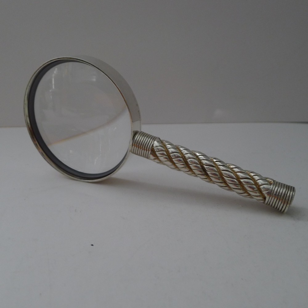 A silver-plated magnifying glass featuring a round frame and a handle styled with a twisted rope motif.