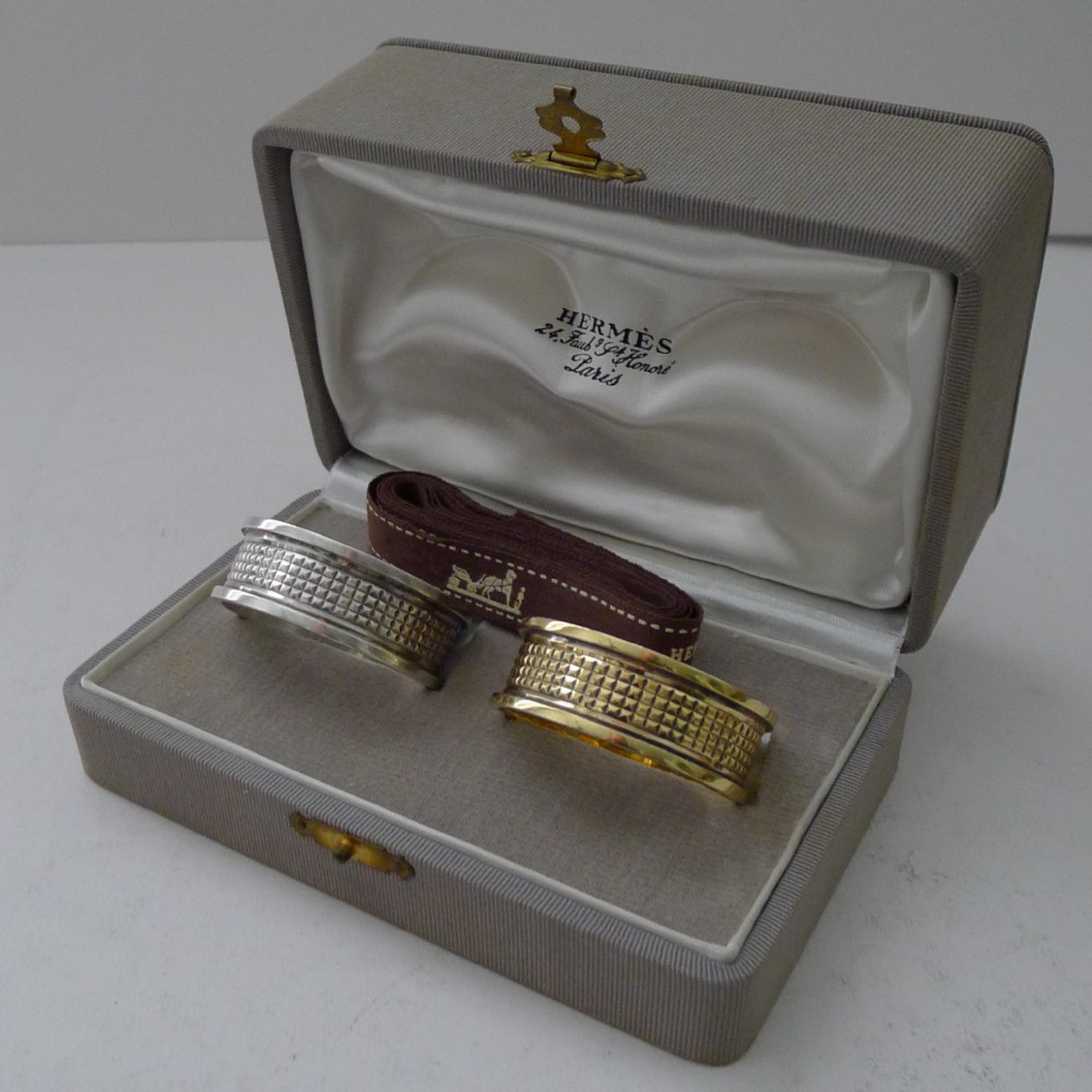 A pair of textured French sterling silver and silver-gilt napkin rings presented in an original fitted grey fabric Hermes presentation box.