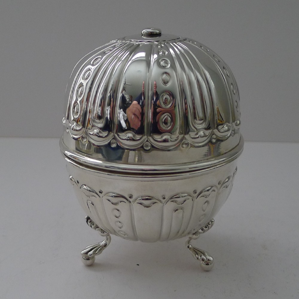 A spherical polished silver string box featuring embossed fluted decoration, intricate beaded detailing, and resting on three cast feet.