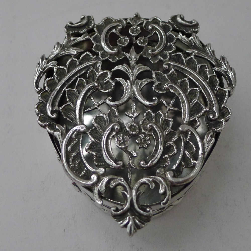 A heart-shaped sterling silver pot pourri box featuring intricate pierced scrollwork and foliage motifs across the lid.