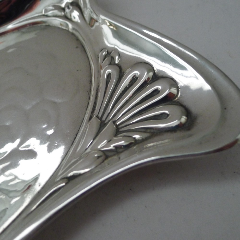 A shaped sterling silver dressing table tray featuring embossed cherub heads surrounded by clouds and stylized Art Nouveau scrolling borders. View VIII