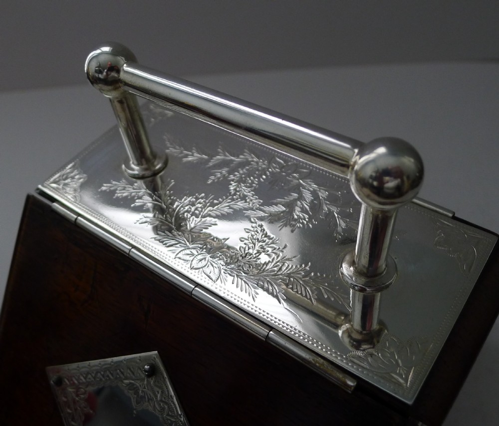 A dark oak biscuit box featuring a slanted hinged lid with a silver-plated handle, a blank silver-plated cartouche on the front, and side crest mounts. View III