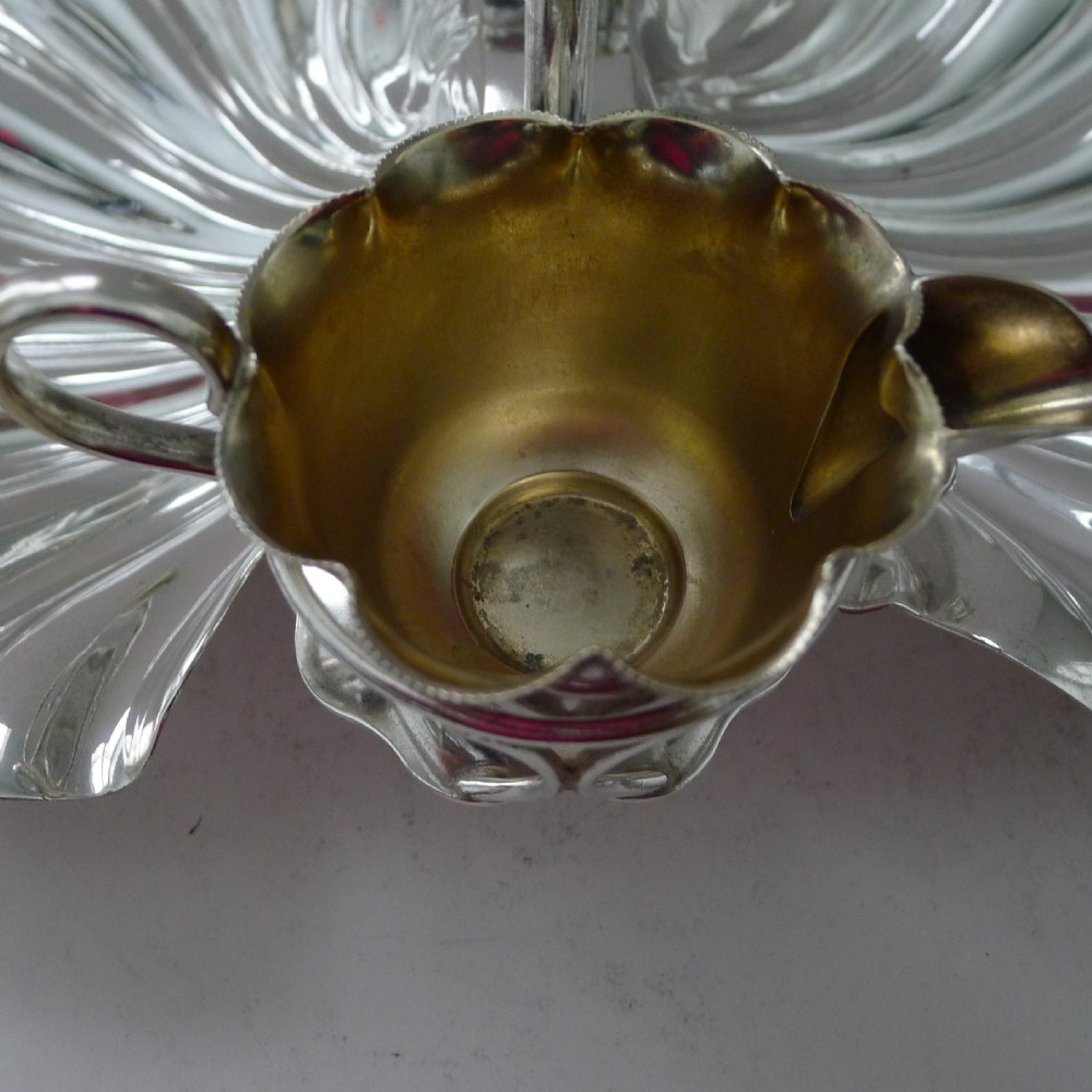 An antique silver-plated strawberry set featuring two fluted shell-shaped serving dishes, a central overhead loop handle, and two small gilt-lined pots. View VII