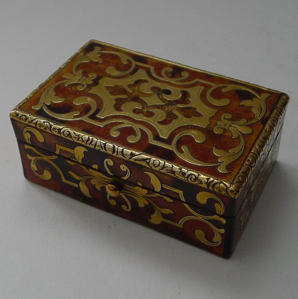 A small rectangular 19th-century French Boulle trinket box featuring intricate brass foliate inlay over a tortoiseshell pattern with chased metal edging.