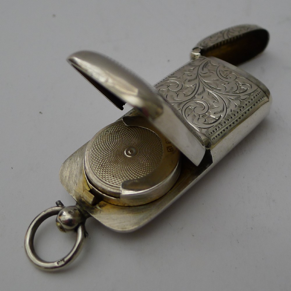 An open Edwardian sterling silver combined sovereign holder and vesta case with hand-engraved foliate patterns and a suspension ring.
