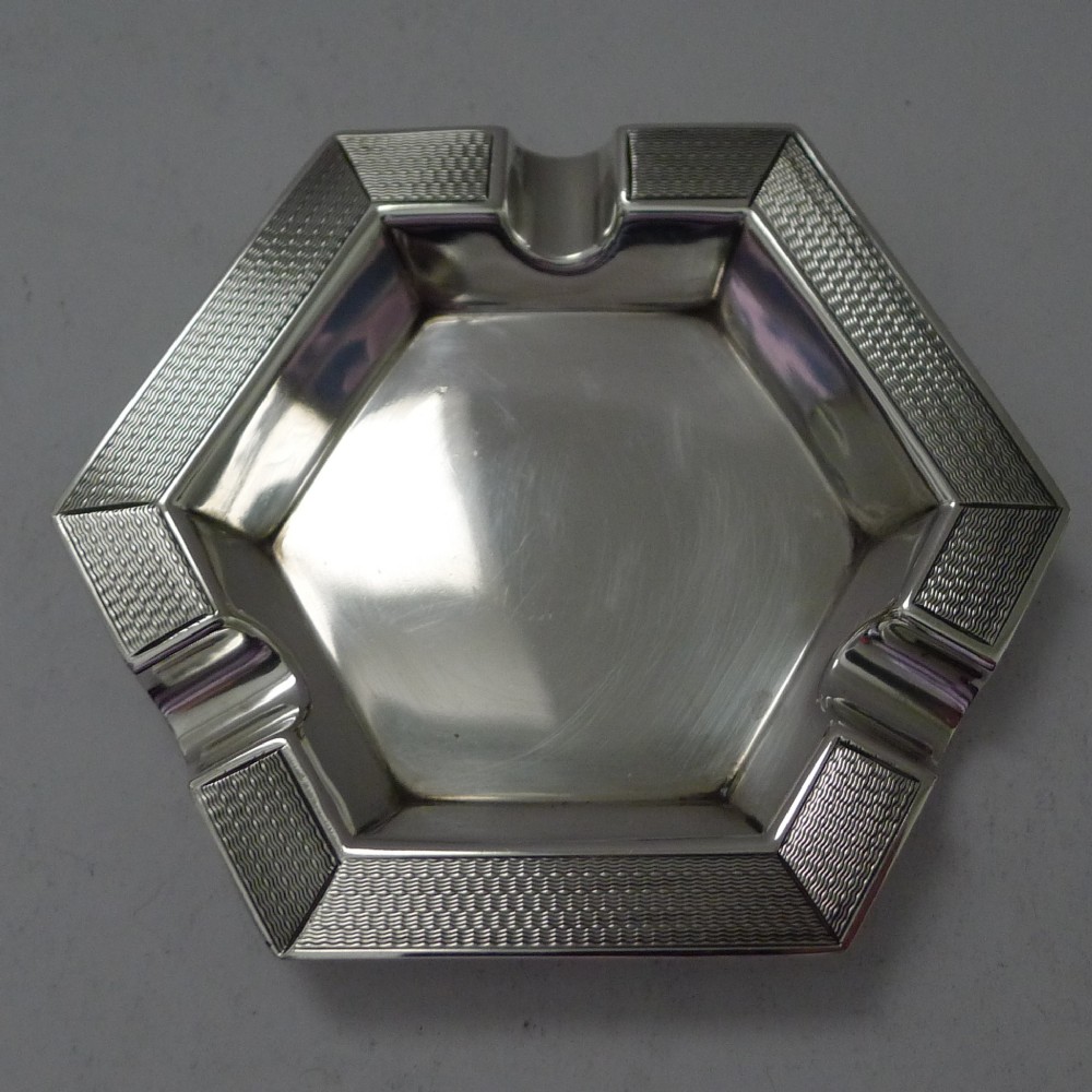 An Edwardian hexagonal sterling silver ashtray featuring engine-turned geometric textured rims and cigarette rests.