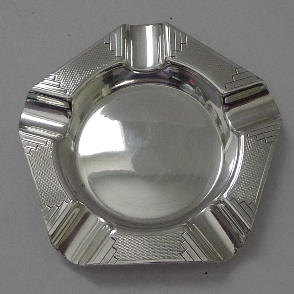 A pentagonal sterling silver Art Deco ashtray featuring geometric stepped corners, engine-turned engraving, and five integrated cigarette rests.