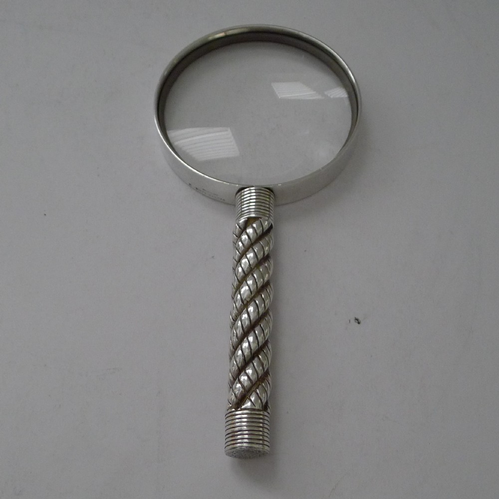 A vintage silver-plated magnifying glass featuring a circular lens and a textured twisted rope pattern handle.