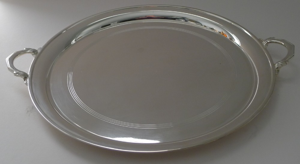 A circular silver-plated Art Deco cocktail tray featuring concentric line engraving on the flat surface and two stylized side handles. View VIII