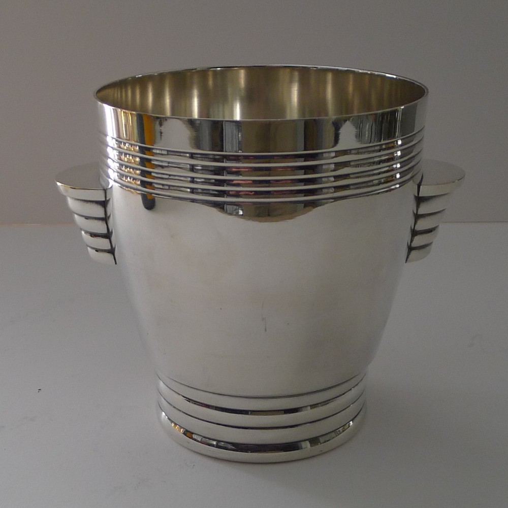 A silver-plated Art Deco ice bucket featuring a tapered silhouette, horizontal ribbed bands, and stylized stepped side handles.